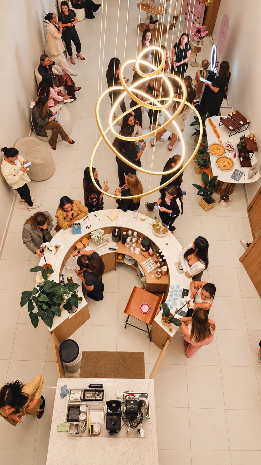 O clube visto de cima, com o lustre de anéis dourados e pessoas reunidas no balcão